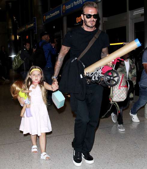 Дэвид Бекхэм несет в руках игрушечное инвалидное кресло для куклы Харпер