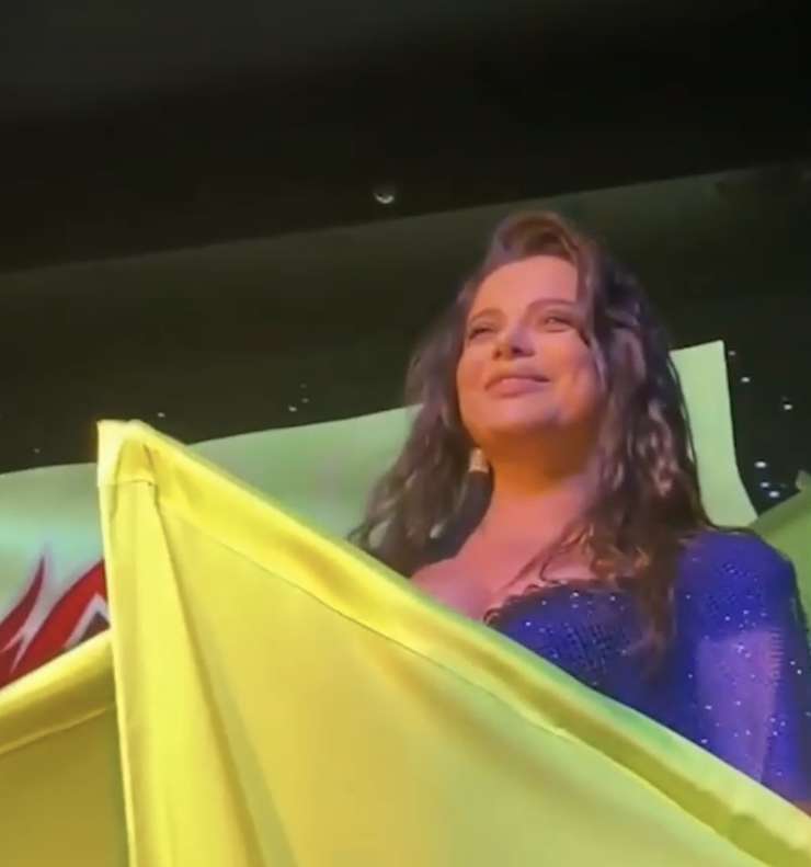Певица вышла в синем платье на фоне желтых лент
