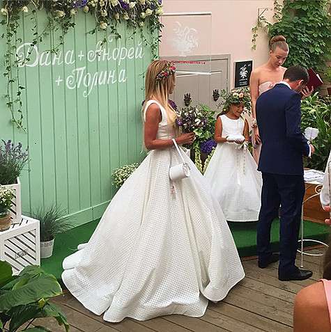 В фотозоне, оформленной живыми цветами, на светло-зеленой деревянной стене красовалась надпись: «Дана+Андрей+Полина». Фото: Instagram.com.