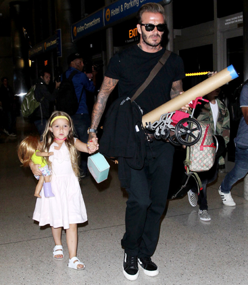 Дэвид Бекхэм несет в руках игрушечное инвалидное кресло для куклы Харпер